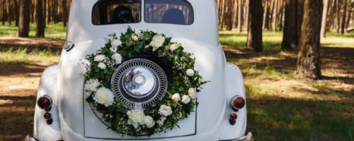 Wedding car with a decoration in the form of a wreath and the word “Wedding”