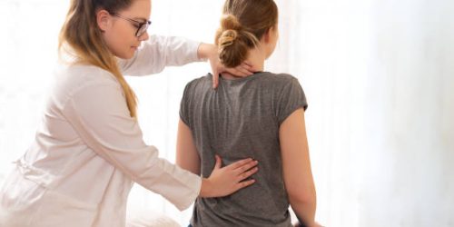 istockphoto-1200969340-612×612 Female physiotherapist or a chiropractor examining patients back. Physiotherapy, rehabilitation concept.