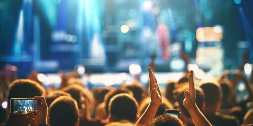 istockphoto-1311329449-170667a Rear view of large group of people enjoying a concert performance. There are many hands applauding and taping the show.